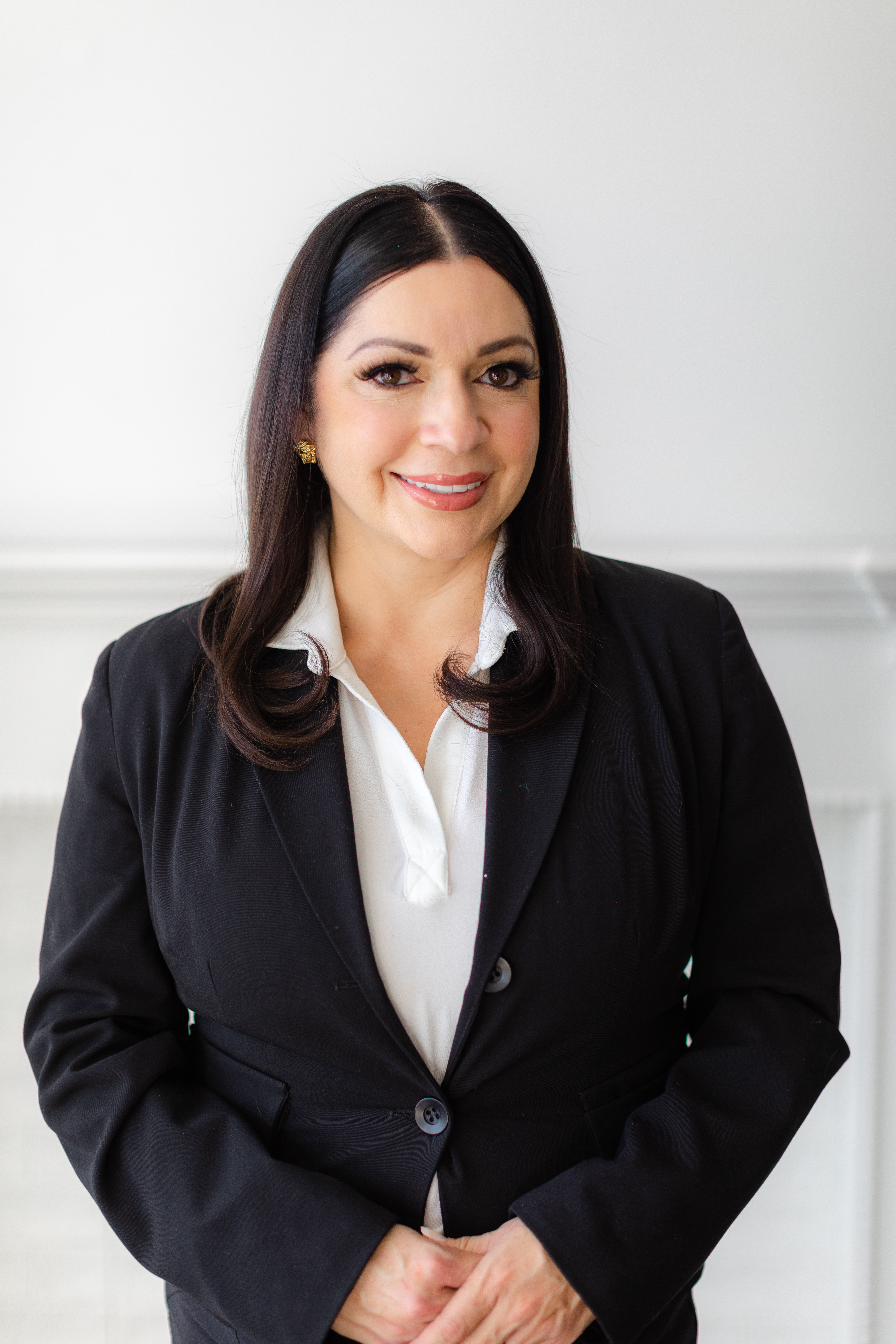 Anabel smiling at the camera wearing a white shirt and black blazer.